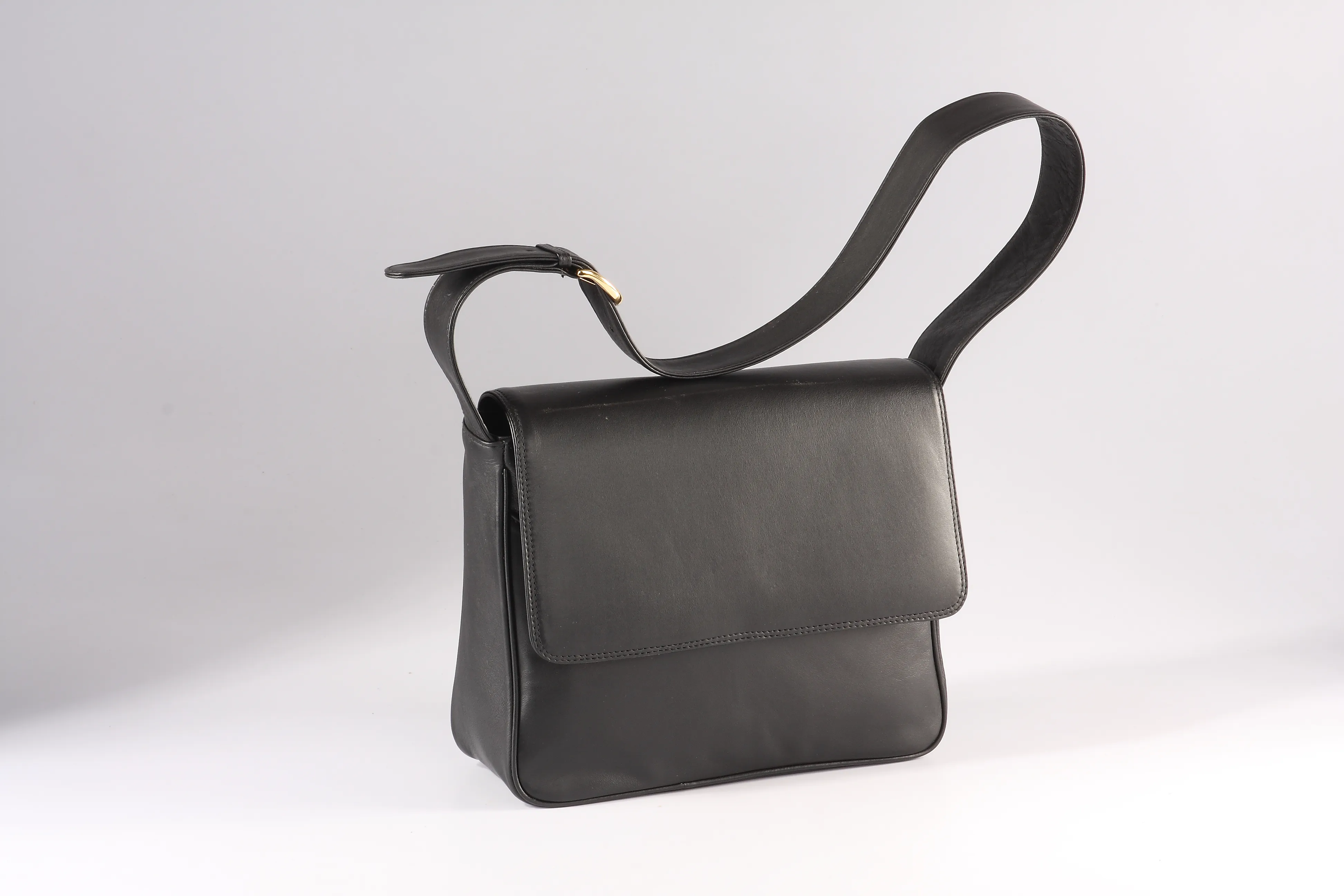 Black Nappa leather shoulder bag with a flap and magnetic snap, adjustable strap, and broad shoulder flap. Includes multiple compartments and pockets.