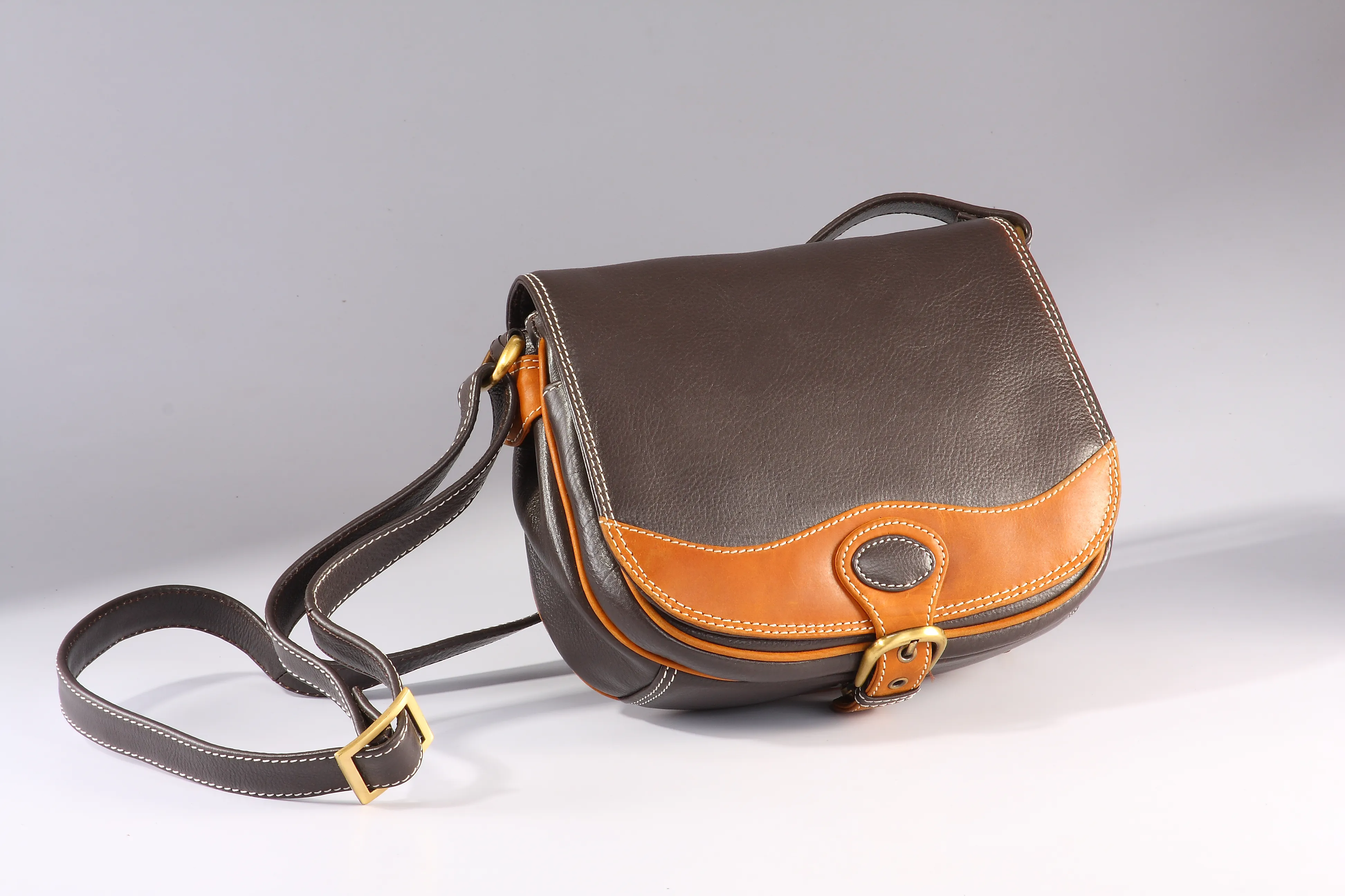 Black and tan combination NDM leather handbag, featuring 2 front pockets, centre zip pocket, 2 compartments, under-flap pocket with fabric lining, and back zip pocket.