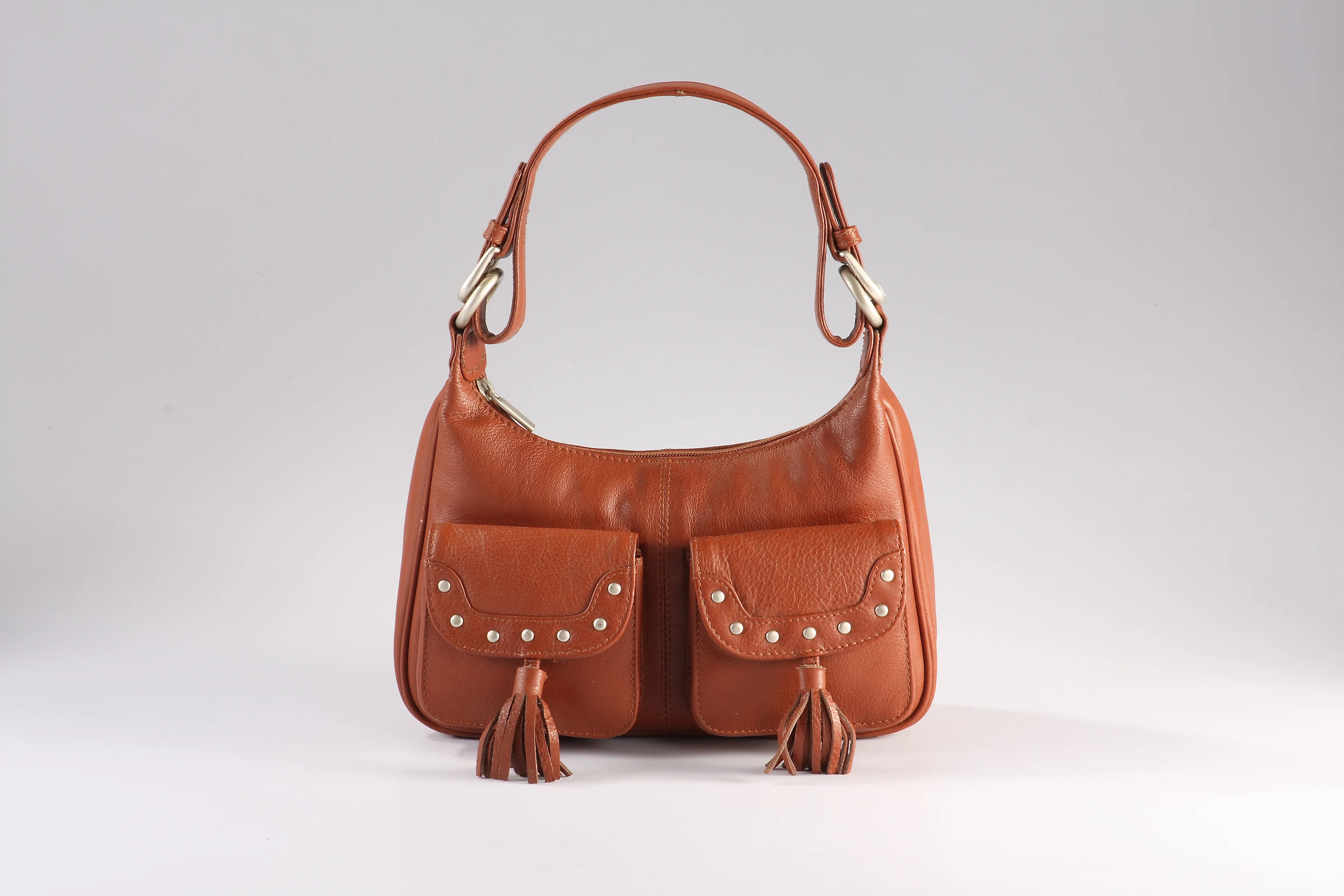 Tan NDM leather handbag with two front flap pockets studded with rivets, fabric partition, and a top zip compartment.